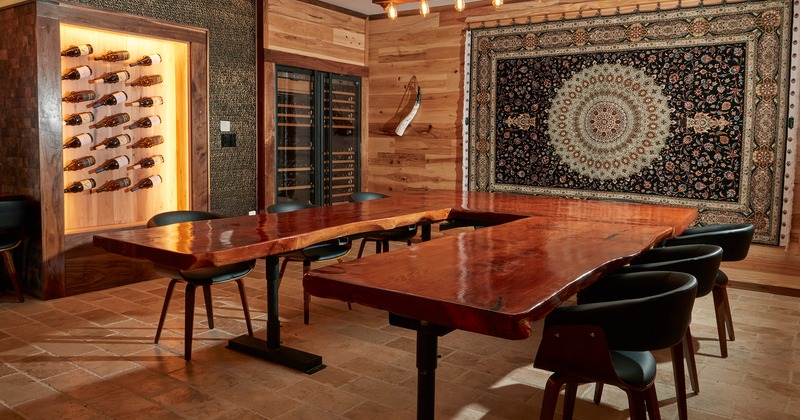 Private parties room with large wooden table, wine rack with assorted wines on the wall