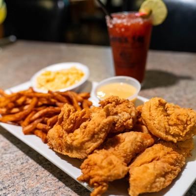 Fried chicken tenders with fries, mac and cheese, dipping sauce, and a cocktail.
