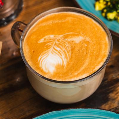 Cappuccino served in a clear glass mug with latte art.