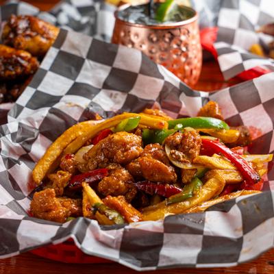 Fried chicken and peppers served in checkered paper with a copper mule cocktail.