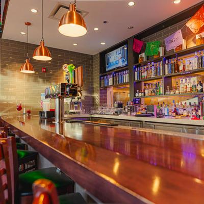 Long wooden bar with copper pendant lights.