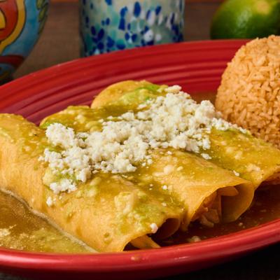 Chicken enchiladas with green salsa, cotija cheese, and seasoned rice.