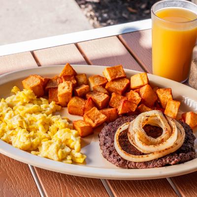 Steak, eggs, and potatoes with orange juice.
