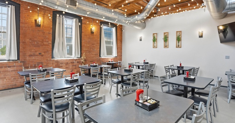 A modern, cozy restaurant interior with brick walls and large windows