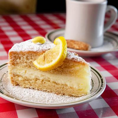 Italian Lemon Creme Cake topped with powdered sugar and a lemon wedge.