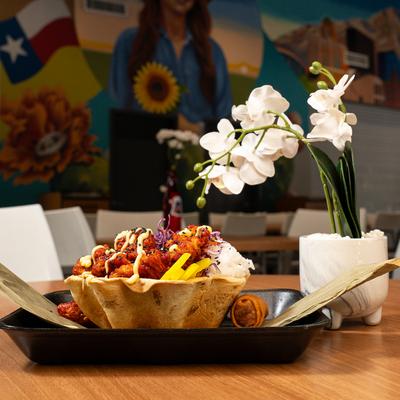 Spicy Chicken Buldak Rice Bowl on a table with white orchid in a white vase.