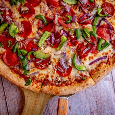 Pizza topped with pepperoni, cheese, green bell pepper and onion, close-up.
