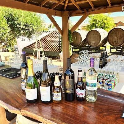 Outdoors, assorted bottles of beer and wine on a bar counter.