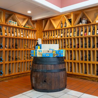Wooden wine display with assorted wine bottles and pasta boxes on a rustic barrel table.