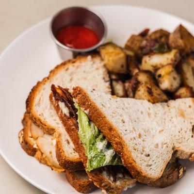 Turkey club sandwich served with home fries and a dipping sauce.