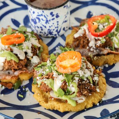 Birria sopes served with sauce on a decorative plate.