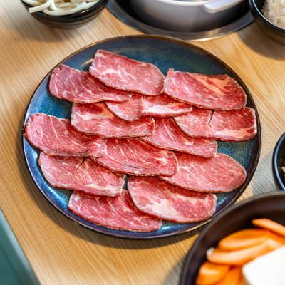 Thinly sliced red meat, placed on a plate.
