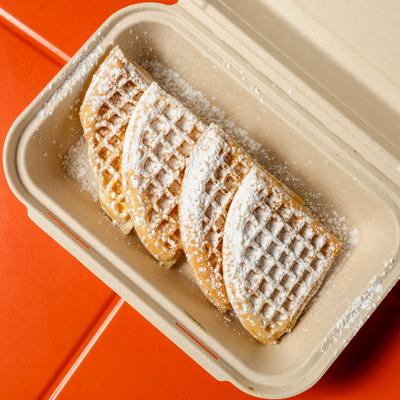 Waffles served in a disposable container and topped with powdered sugar.