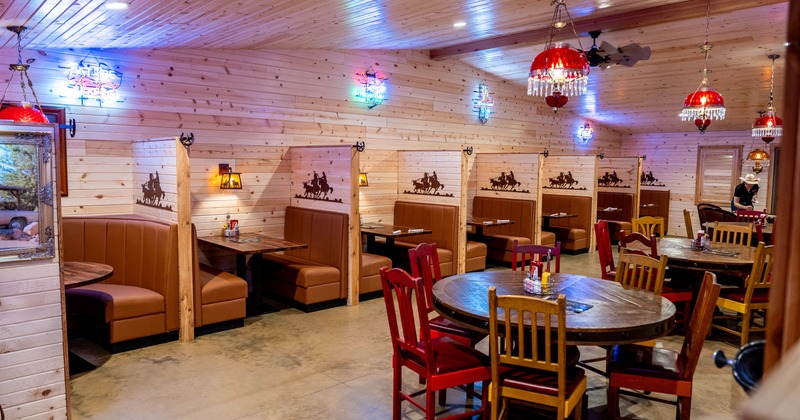 Rustic restaurant interior with wooden booths, Western decor, and red pendant lights