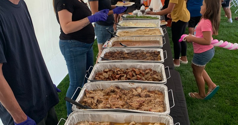 Inside a tent, people helping themselves to food from buffet plates