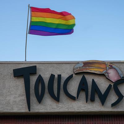 Toucans exterior sign with a rainbow flag above.