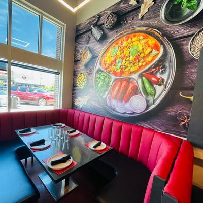 Interior featuring a large booth table set for guests and food-themed wallpaper.