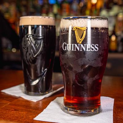 Two pints of dark beer on the bar counter.