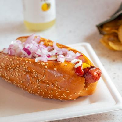 Hot dog topped with diced onions and mustard.