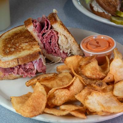 Woodward reuben sandwich served with potato chips and a dipping sauce.