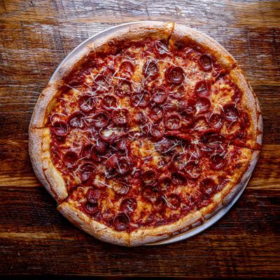 Pepperoni pizza served on a rutsic wooden table.