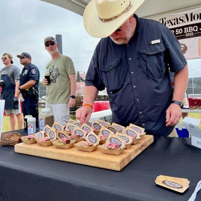 Outside, Lance Eaker, the owner of Eaker Barbecue, standing by a promotional table with dishes
