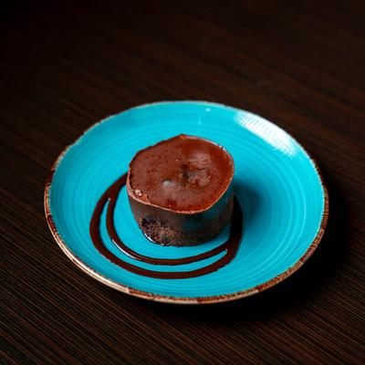 Vegan Chocolate Cake with drizzled chocolate sauce on a blue plate.