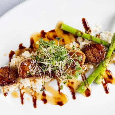 Seared scallops over risotto with asparagus, microgreens, and balsamic glaze.