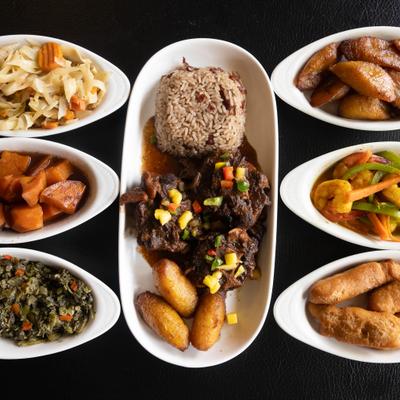 Oxtail with plantains and rica, served alongside warious side dishes.