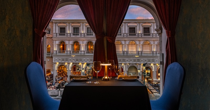 Set dining table for two next to a window, with a view at the building outside