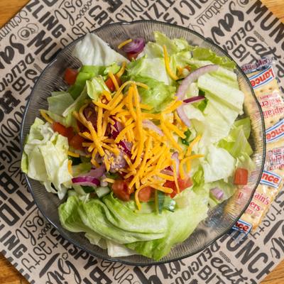 Garden salad topped with shredded cheddar cheese.