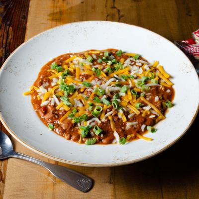Spicy chili under melted cheddar and fresh diced onions.