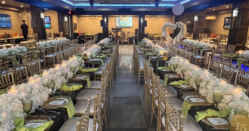 Wedding banquette room with tables, wedding flower decor and tableware on them