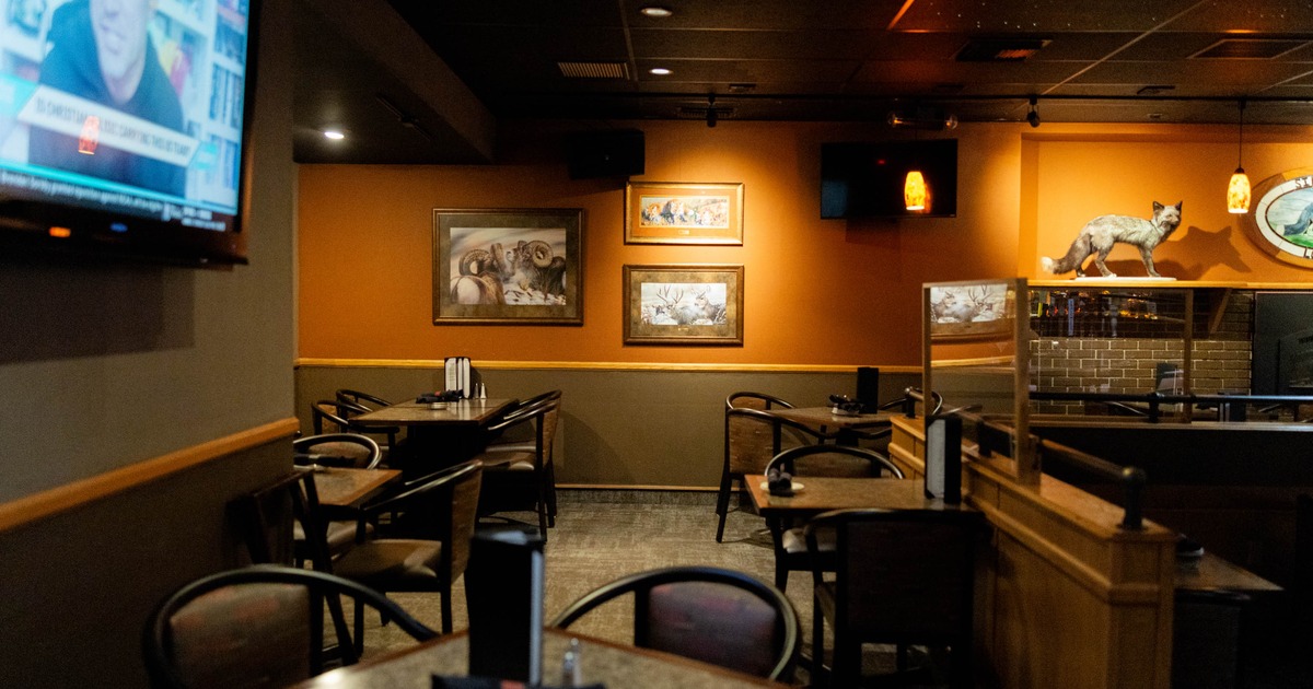 Interior view of a restaurant with empty tables, framed wildlife art on orange walls