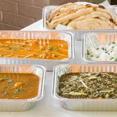 Aluminum trays with Nepalese food are displayed on a table.