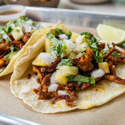 Pork al pastor tacos topped with onion and pineapple.