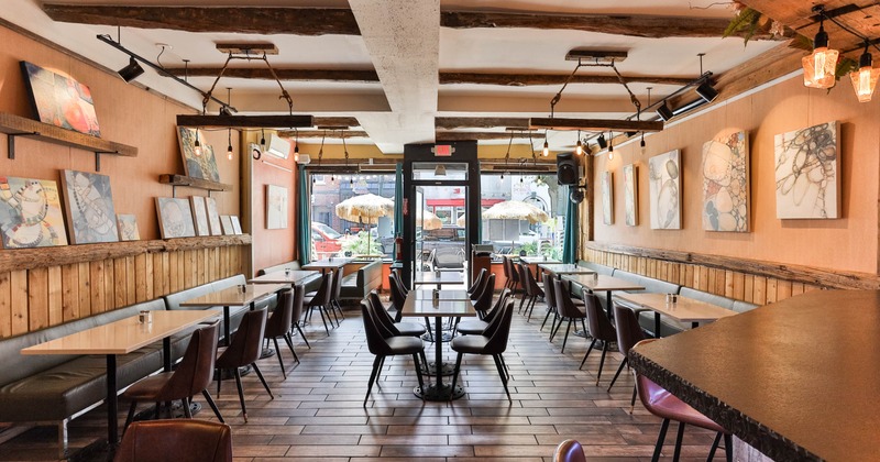 Interior, wooden floors, tables aligned along the walls, abstract art, and large windows
