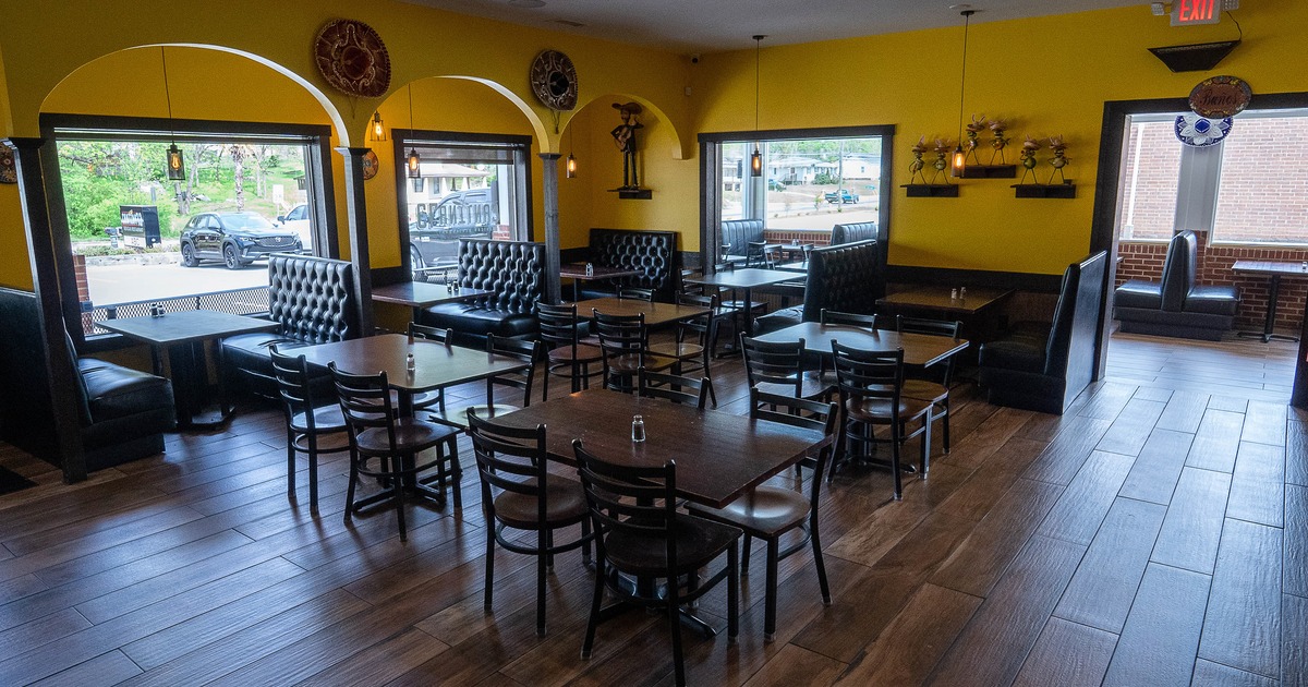 Cozy interior dining area with wooden tables and chairs, and upholstered booths