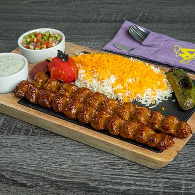 Two ground beef skewers served with with white and saffron rice, a salad, dipping sauce.