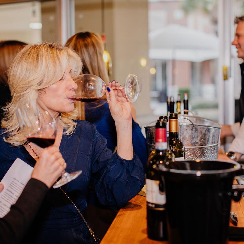 Person sipping wine at the bar counter.