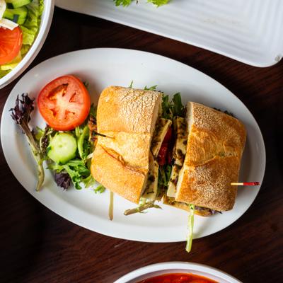 Chicken pesto sandwich served with salad on the side.