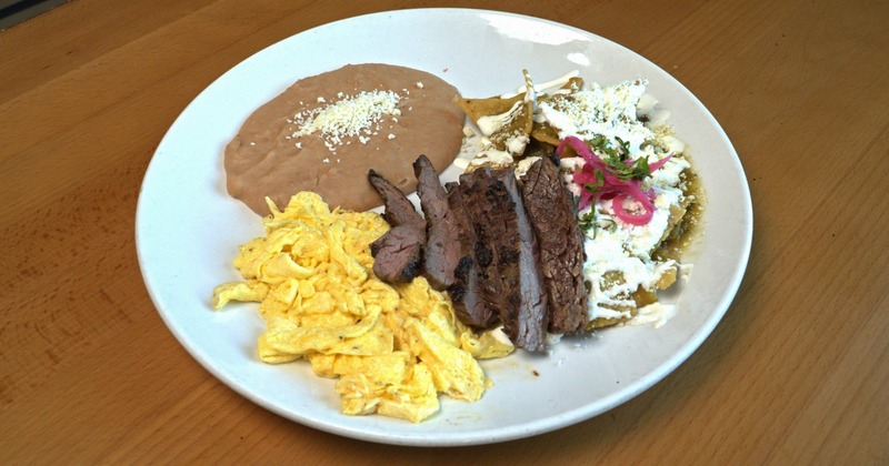 Steak strips with scrambled eggs, beans, and tortilla strips with green sauce and sour cream