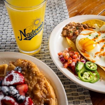 Huevos Rancheros served with a glass of orange juice and chicken and waffles with berries.