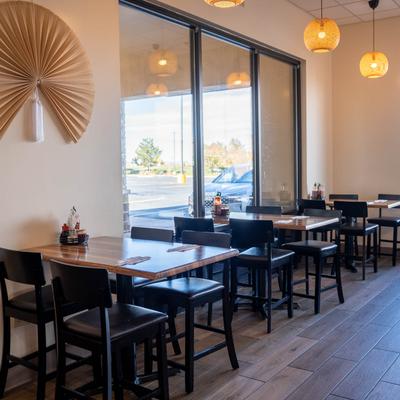 Interior with tables, large windows, and a bamboo fan on the wall.