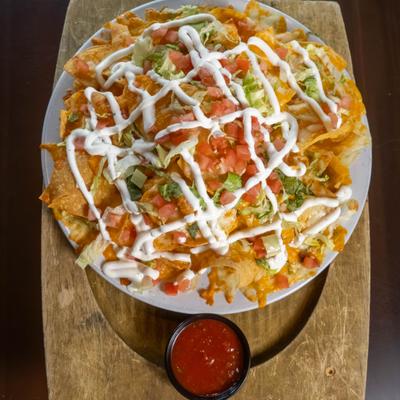 Ultimate Nachos topped with diced tomato, lettuce and drizzle of sauce, served woth salsa on the side.