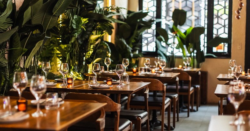 Dining tables set with wine glasses, plates, and softly glowing candles