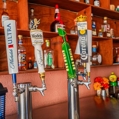 Four beer tap handles at a bar featuring various Mexican and American brands.