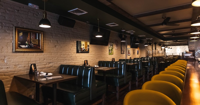Interior of a restaurant with green booth seating and yellow bar stools