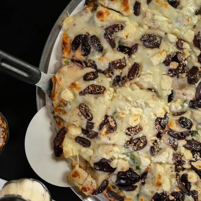 Greekin Out Pizza with chicken, feta, spinach, Greek olives and white sauce.