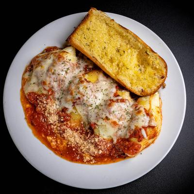 Baked Stuffed Shells, smothered in marinara, cheese, and served with garlic bread.
